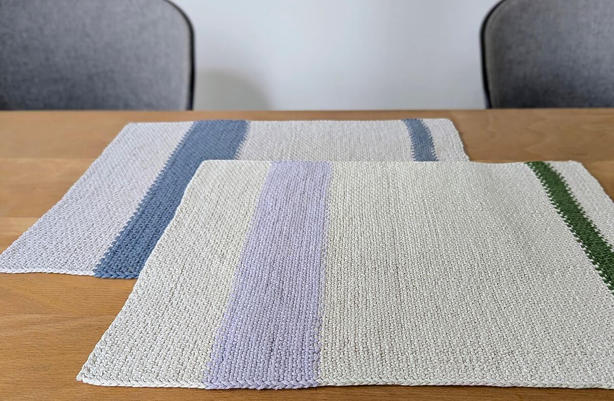 Beitragsbild zu handgestrickten Tischsets ready - zwei Varianten auf einem Esstisch mit Holzplatte