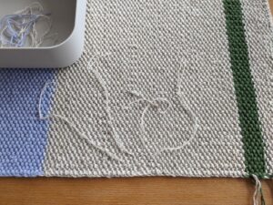 Rückseite des Tischsets ready beim Fäden vernähen. Garnenden sind in dünne Fäden aufgezwirbelt.